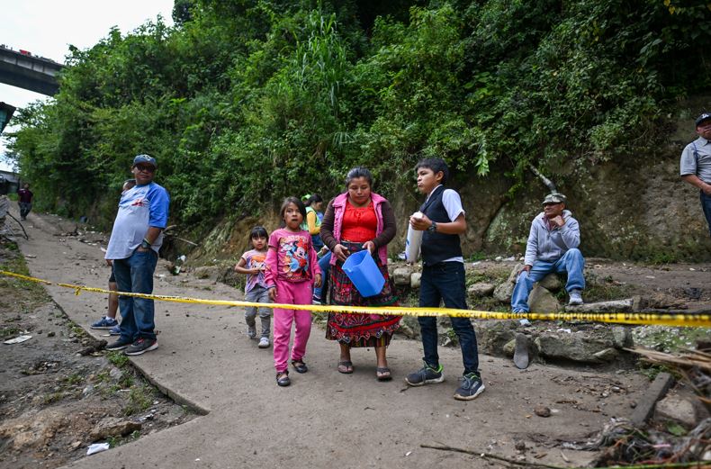 Locals look at the place where the current of a river swept away several houses at Dios es Fiel shantytown, an annex of the Kjell Laugerud colony in Guatemla City. Photo Credit: AFP